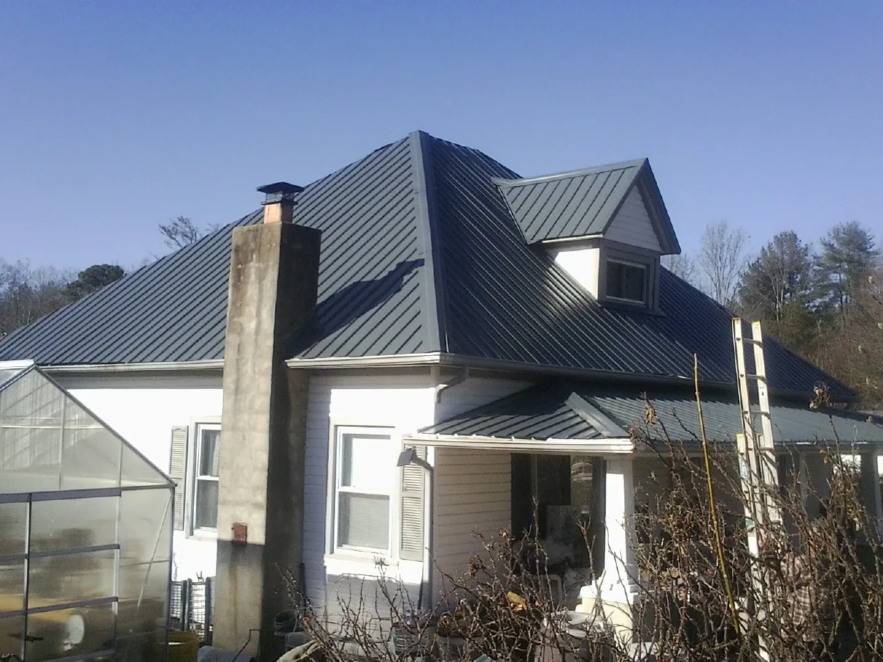 Dark blue standing seam metal roof on a white farmhouse with dormer — Slate & Tile Roof Repair by Roofing Brothers in Marcellus