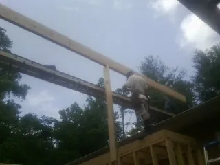 Carpenter setting a ridge beam over a new addition frame — Ice Dam Removal by Roofing Brothers in Marcellus