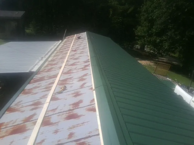 Old rusted panels beside newly installed green metal roofing — Wind Damage Roof Repair by Roofing Brothers in Marcellus