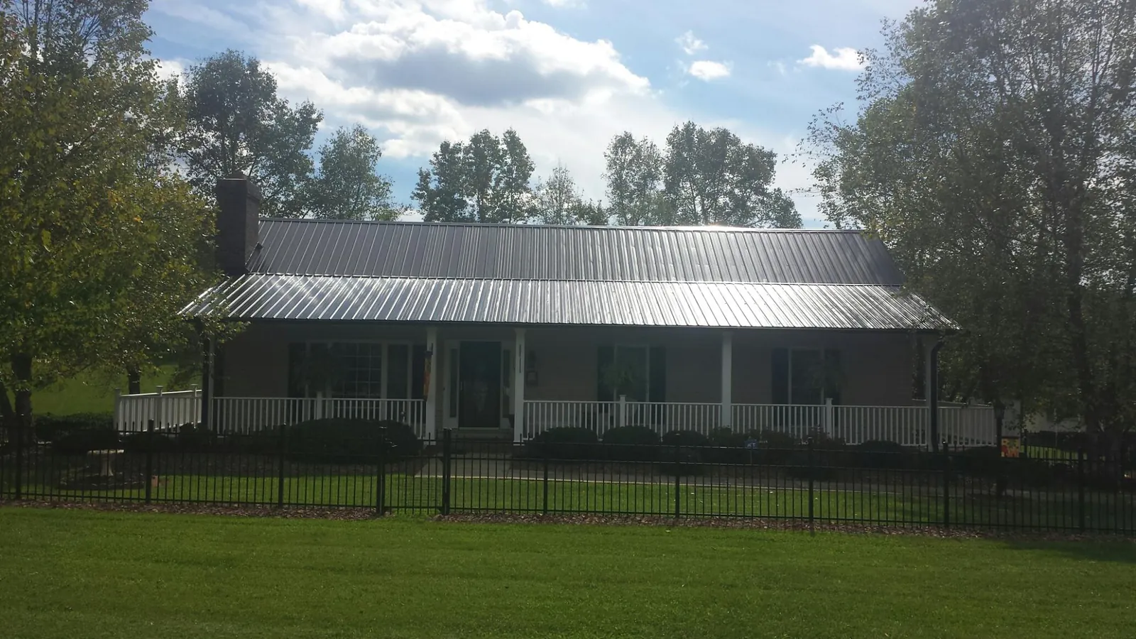Gray metal roof on a brick ranch with a full width front porch — Gutter Guard Installation work by our crew in Marcellus